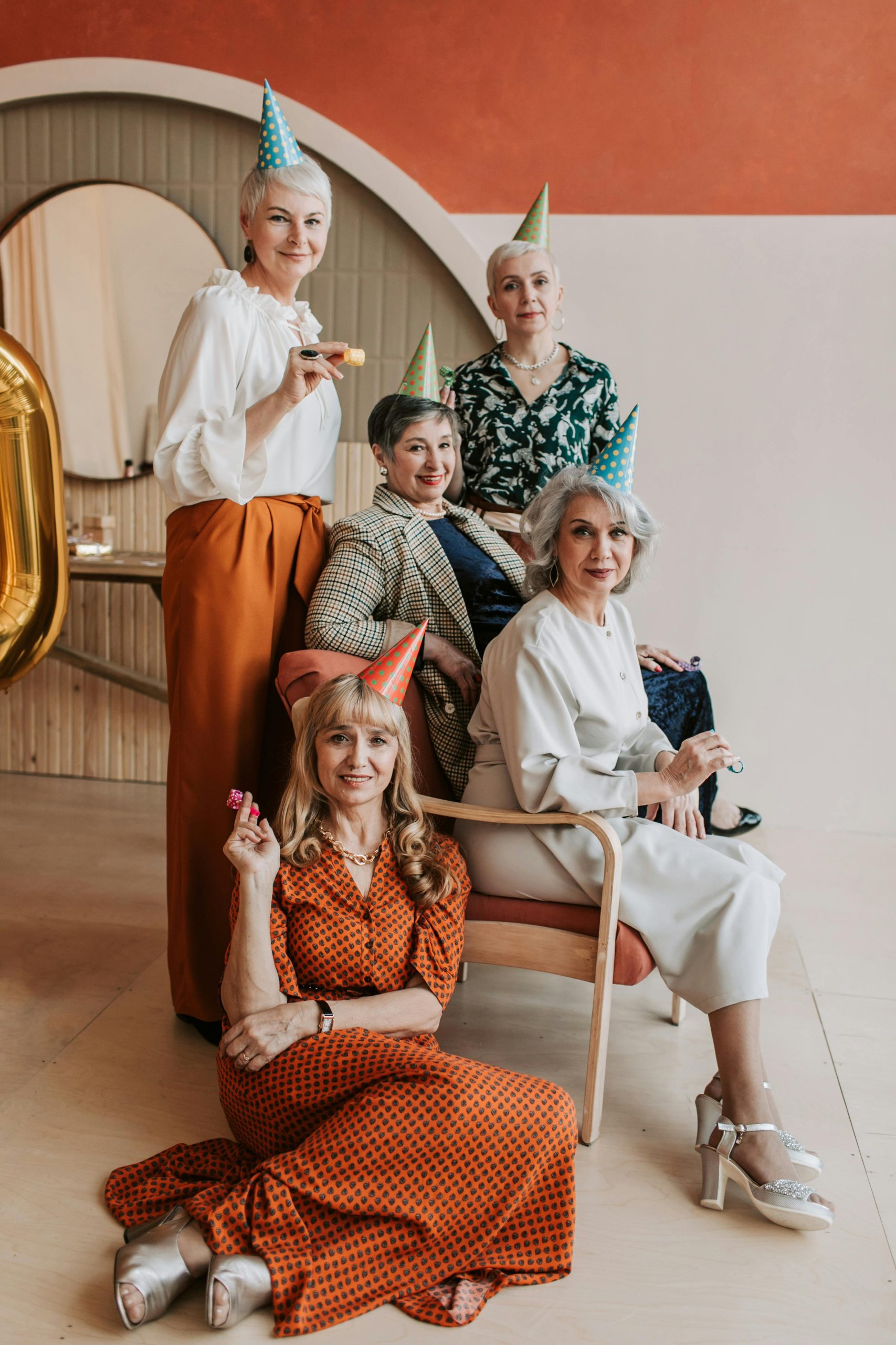 Elegant senior women in festive hats celebrating indoors with joy and style.